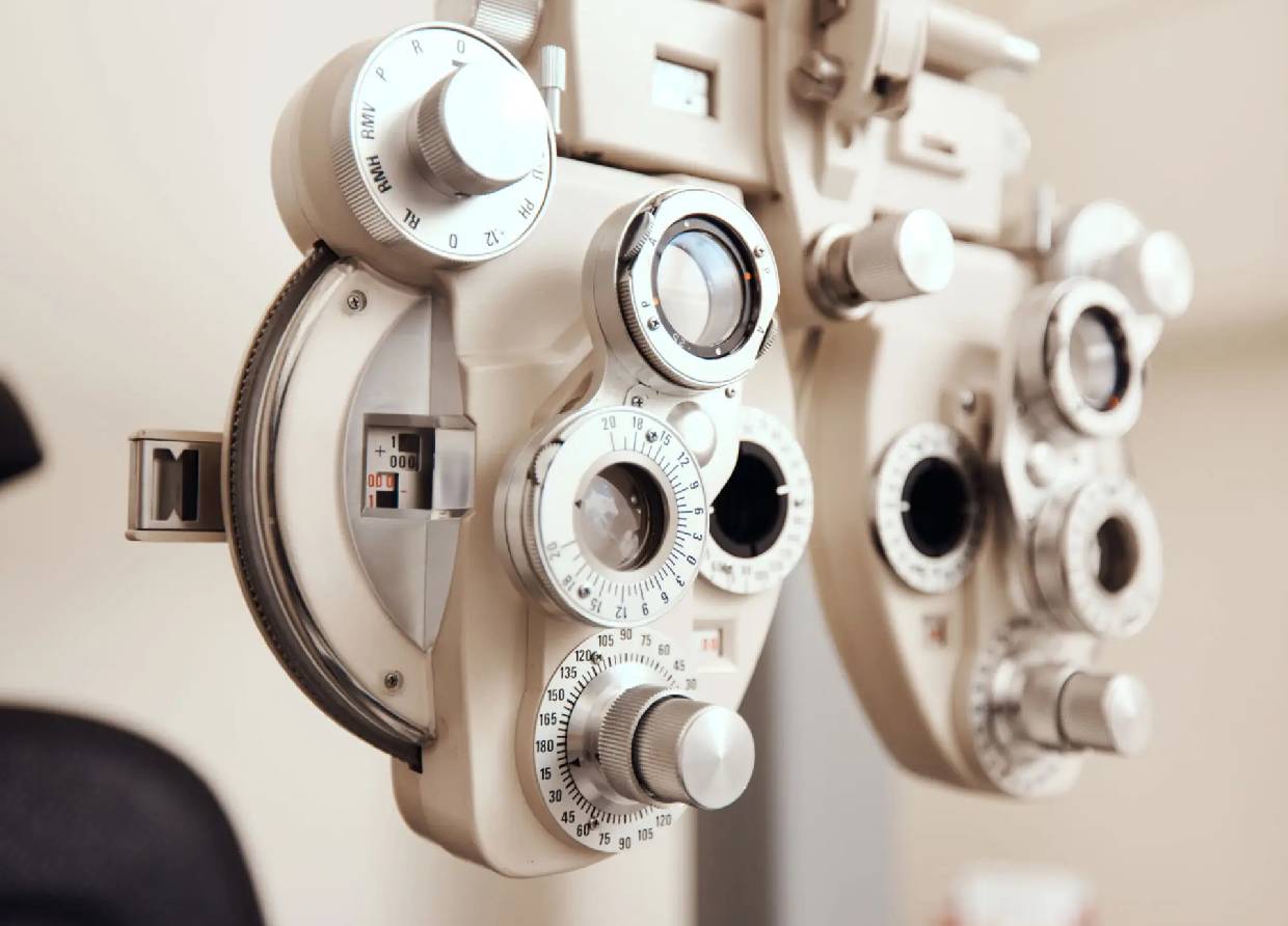 Close-up of an eye examination device with adjustment dials and lenses.